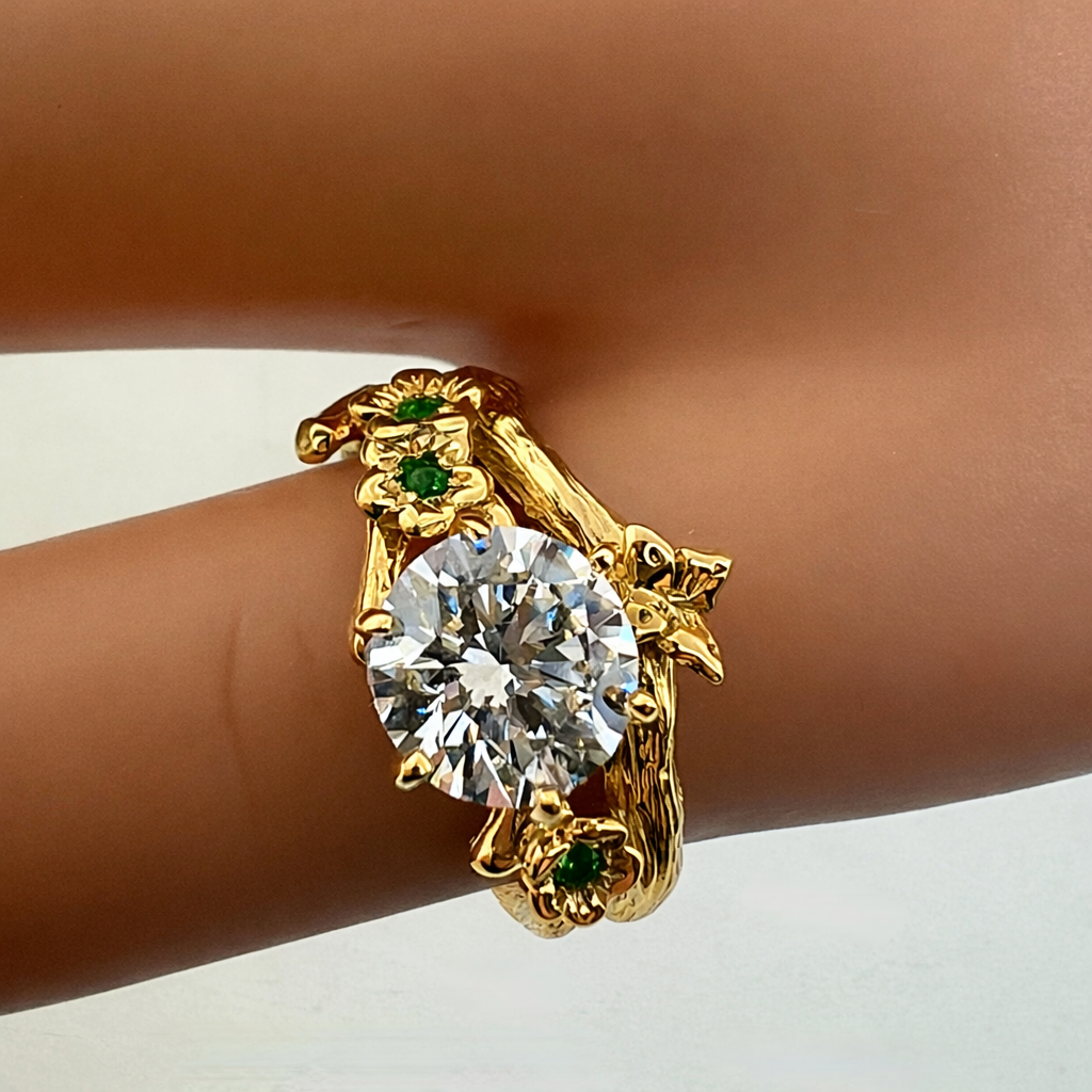 Handcrafted 14k gold bud branch moissanite engagement ring with natural emeralds worn on hand, nature-inspired floral ring made in USA by Teri Lee Jewelry
