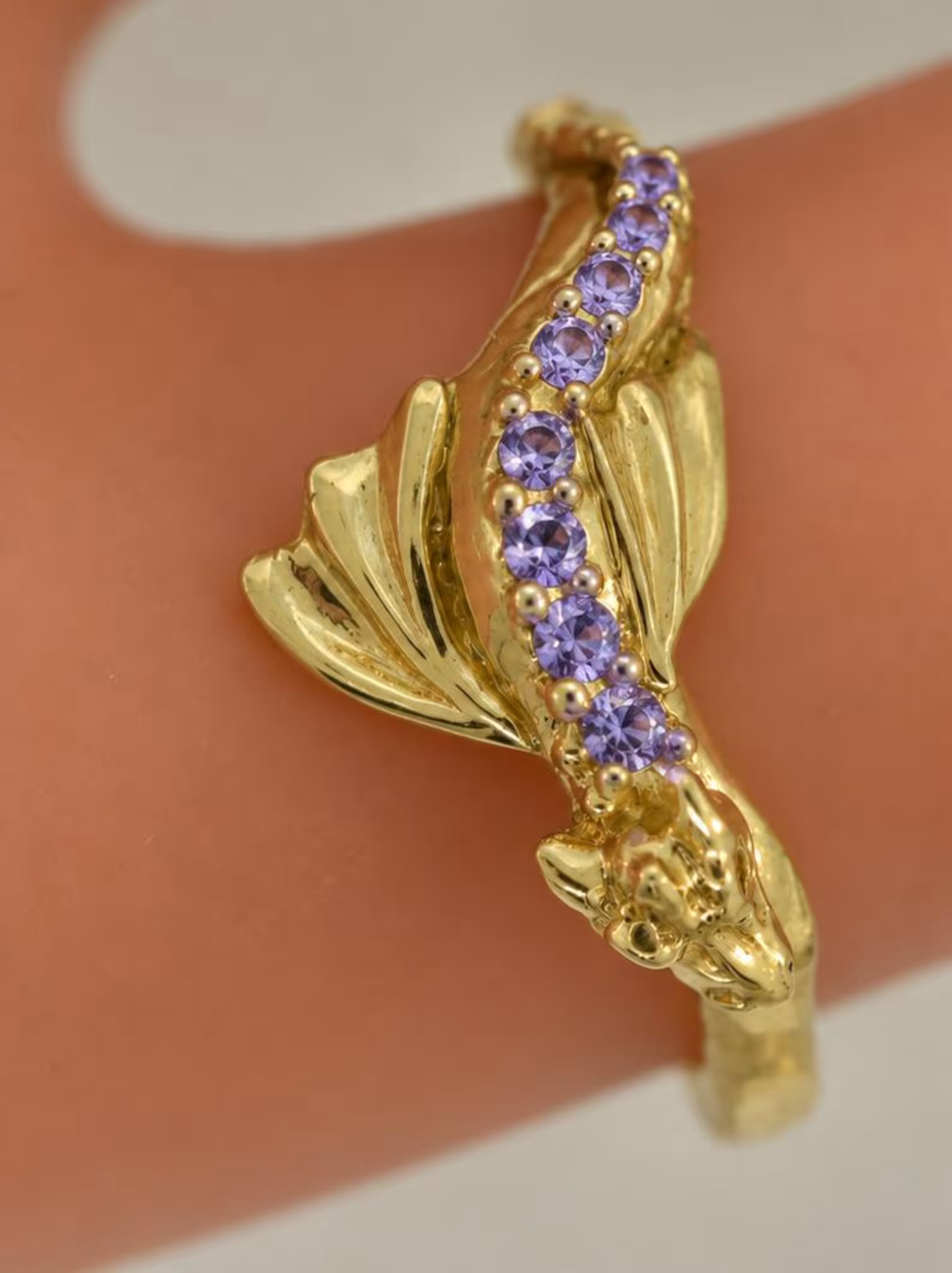 Close-up of a gold Baby Dragon ring with amethysts along its back and sculpted wings, a custom gemstone example.